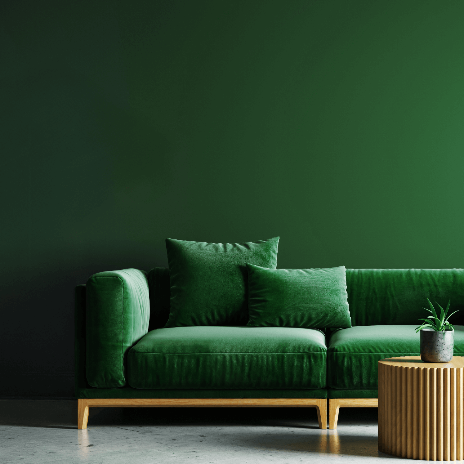 Wandfarbe dunkelgrün auf einer stilvollen Wand, grüner Sofa mit Kissen und runder Holzdeko.